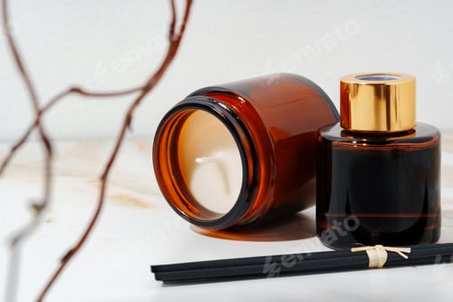 Preview: Brown Glass Candle and Diffuser Bottles on Marble Surface With Dried Branches