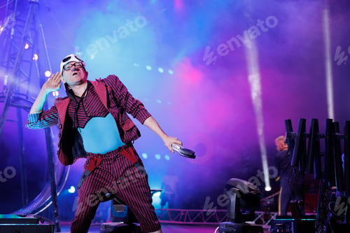 Preview: Clown entertains guests in the circus arena in the light of spotlights and smoke, plays the guitar.