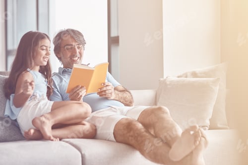 Preview: Father and Daughter Reading Book Together at Home