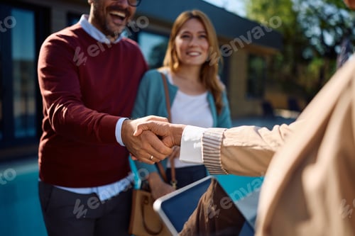 Preview: Close up of real estate agent handshaking with a couple.