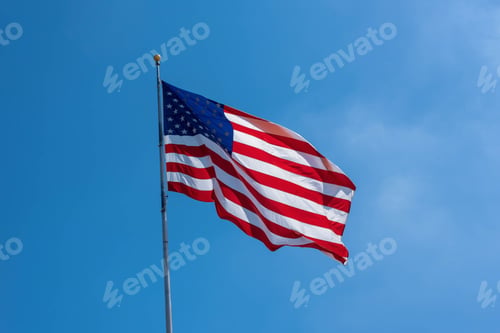 Preview: American flag billowing in the wind against clear blue sky
