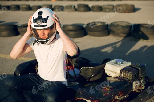 Preview: Young Man Puts On Helmet near Go-Kart