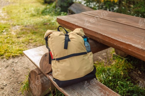 Preview: Travel backpack on wooden log bench in autumn forest with birch trees. Hiking equipment