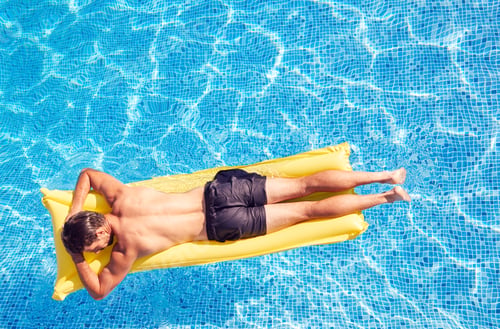 Preview: Overhead Shot Of Man In Swim Shorts Floating On Air Bed On Summer Vacation In Outdoor Swimming Pool