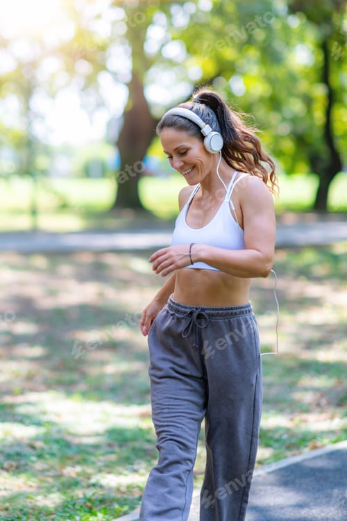 Preview: Woman wearing sportswear and headphones, dancing outdoors for fun and exercise