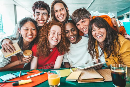 Preview: Multiracial university students sitting together at table with books and laptop