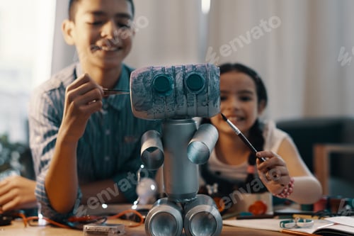 Preview: Shot of two adorable young siblings painting their newly built toy robot at home