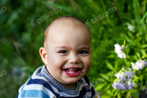Preview: Cute little baby boy outdoors. Happy smiling baby at green garden.