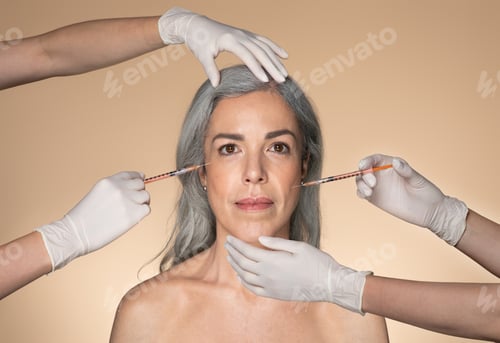 Preview: Beautiful senior woman getting facial injections by two cosmetologists, beauticians giving anti