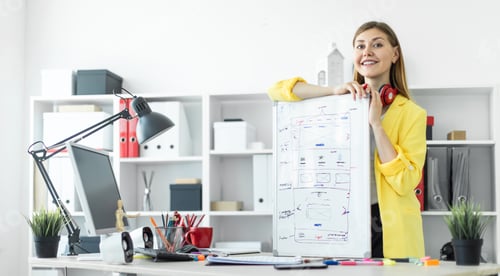 Preview: A young girl stands near a table and holds a marker and a magnetic board in her hands. On the neck