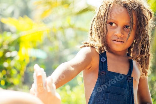 Preview: Mowgli indian boy with dreadlocks hair hiding holding mosquito spray in tropics