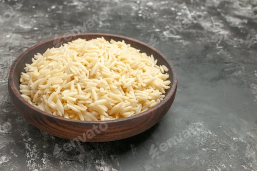 Preview: Side view of boiled rice in a brown wooden pot on the right side on dark background