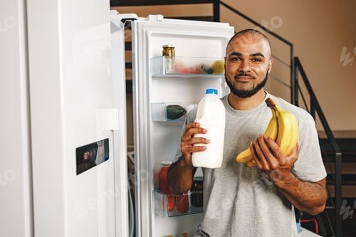 Preview: African american man taking food from a fridge in his house