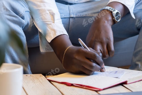 Preview: Closeup shot of a young African American male taking notes and working at home