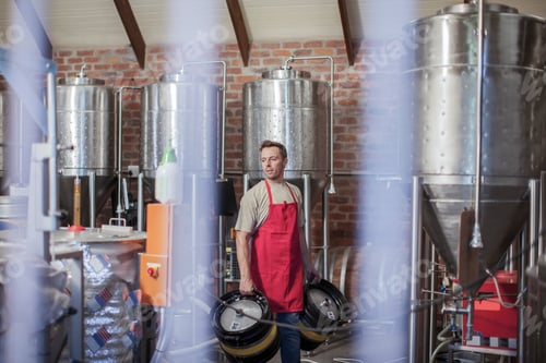 Preview: Man in microbrewery carrying beer kegs