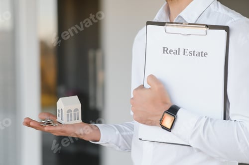 Preview: Real estate agent holding key and house model