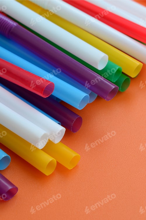 Preview: Many colorful straws for drinks lies on a bright orange background surface