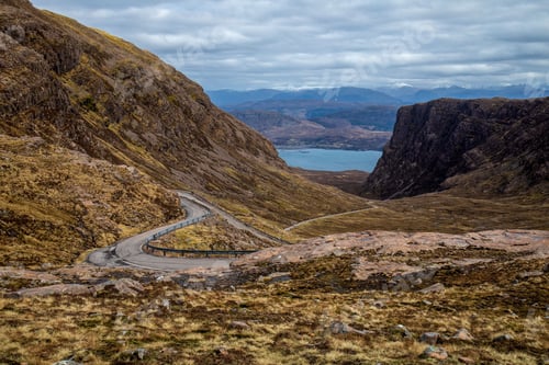 Preview: Winding mountain road with a lake in the background in Scotland