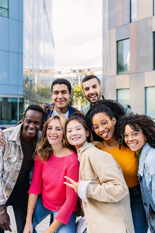 Preview: Vertical portrait of young group of diverse people smiling at camera outdoors.