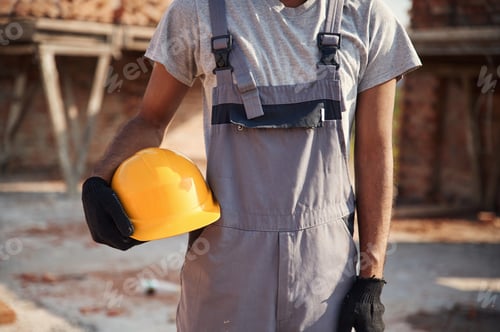 Preview: Holding yellow colored hard hat. Close up view of man that is working on the construction site