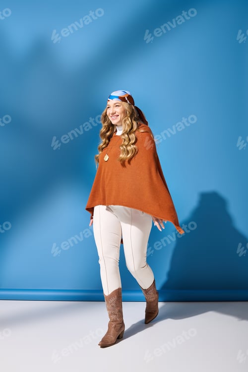 Preview: A cheerful plus size woman in a stylish brown poncho walks confidently against a blue backdrop