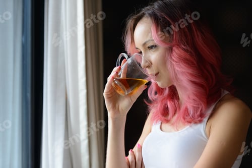 Preview: Face of beautiful woman with pink hair drinking tea and looking out the window