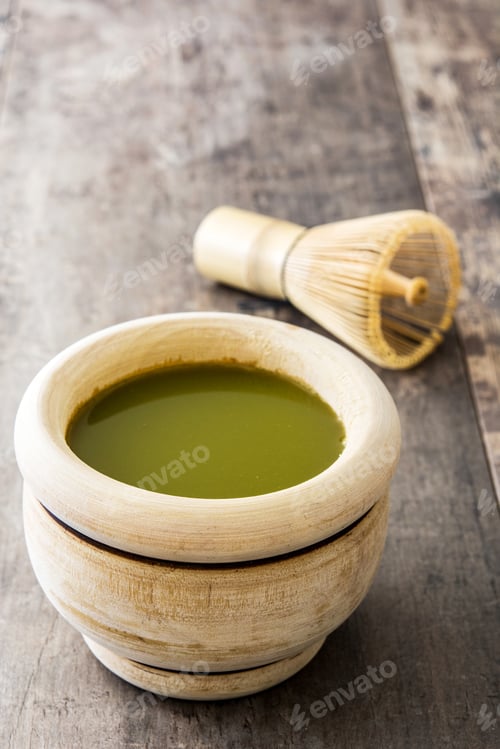 Preview: Matcha tea prepared in wooden bowl with chasen whisk on rustic table
