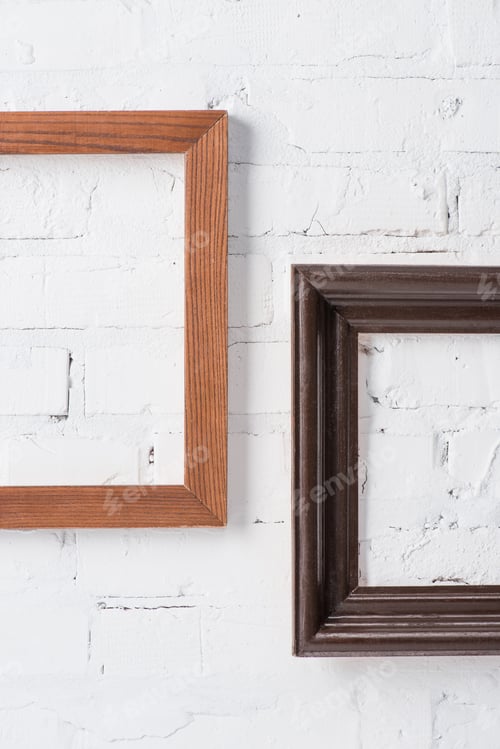 Preview: brown and black empty frames hanging on white brick wall
