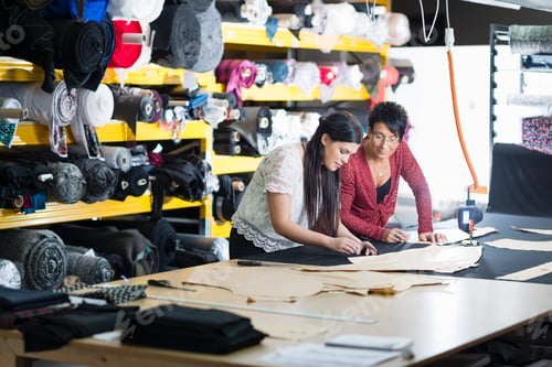 Preview: Two seamstresses chalking design onto textile on work table