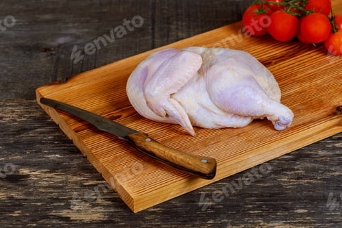 Preview: Raw chicken and vegetables on a wood table part of the chicken on the board for marinating