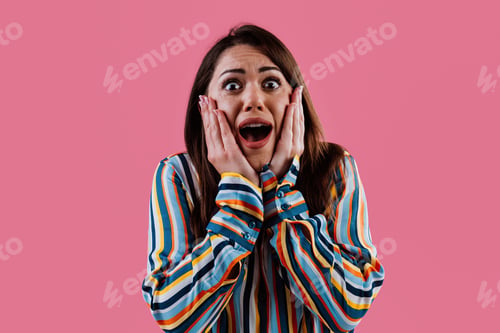 Preview: Young woman expressing surprise and shock on pink background