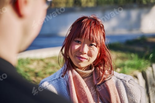 Preview: asian woman looking at her unrecognizable partner.