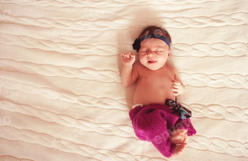 Preview: SLeeping baby in bed on knitted cover closeup. Top view.