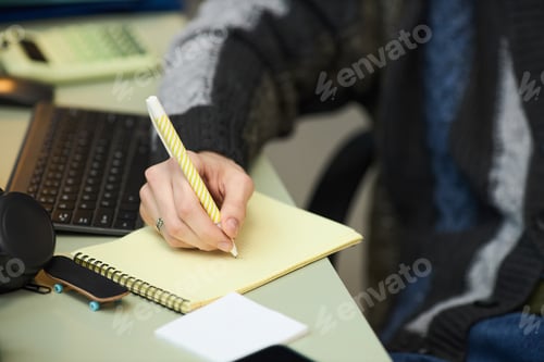 Preview: Young Adult Woman Writing Notes on Notepad While Studying Indoors