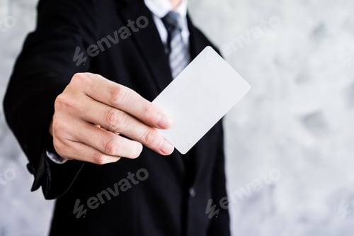 Preview: Close up of businessman holding white blank card on grunge background.