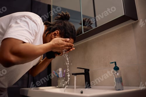 Preview: Black man washing his face in the bathroom.