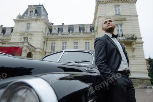 Preview: Man in Suit Near Black Vintage Car