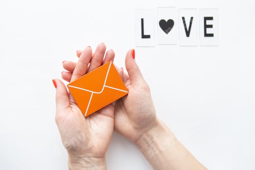 Preview: A love letter holding a small wooden orange envelope. Love lettering.