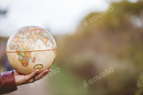 Preview: Closeup shot of a male holding a desk globe with a blurred background