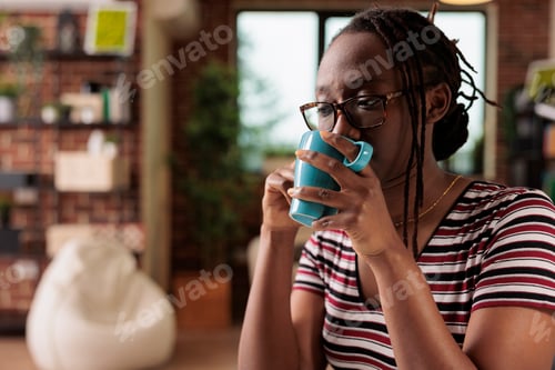 Preview: Young african american woman talking on smartphone, drinking tea