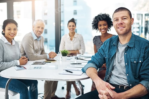 Preview: Portrait of a mature businessman sitting in a meeting with his colleagues in the background