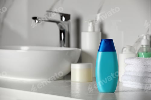 Preview: Bottle of shampoo and stacked towels near sink on bathroom counter, space for text