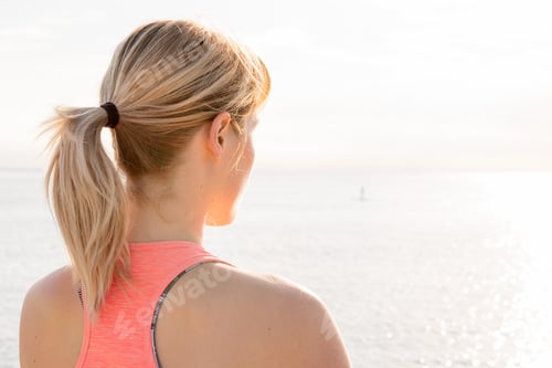 Preview: rear view of a blonde woman doing yoga at sunrise