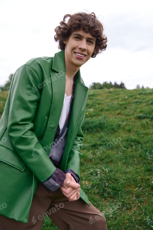 Preview: Young handsome student enjoys a refreshing walk through a lush green field under cloudy skies