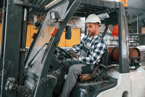 Preview: Forklift driver. Factory male worker in uniform is indoors
