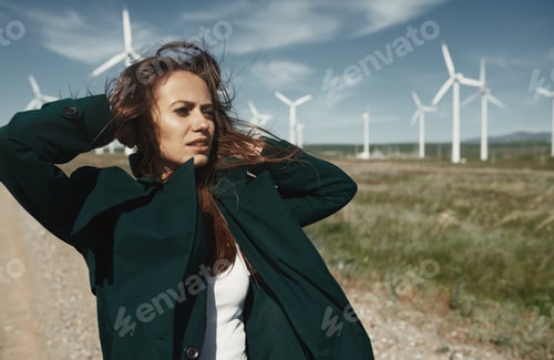 Preview: Woman by wind turbines on a windy day