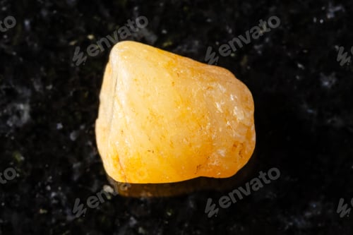 Preview: sample of rough yellow sapphire crystal on black