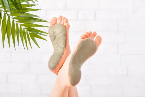 Preview: Beauty care in spa. Foot care with clay on white brick wall