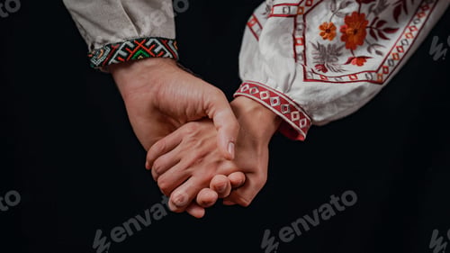 Preview: Young ukrainian couple in embroidered national shirts holding hands. Man and woman on black