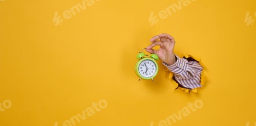 Preview: Woman's hand holds a round green alarm clock